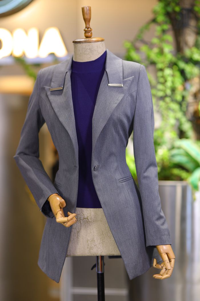 why-choose-us Sophisticated gray blazer showcased on mannequin in fashion store setting.